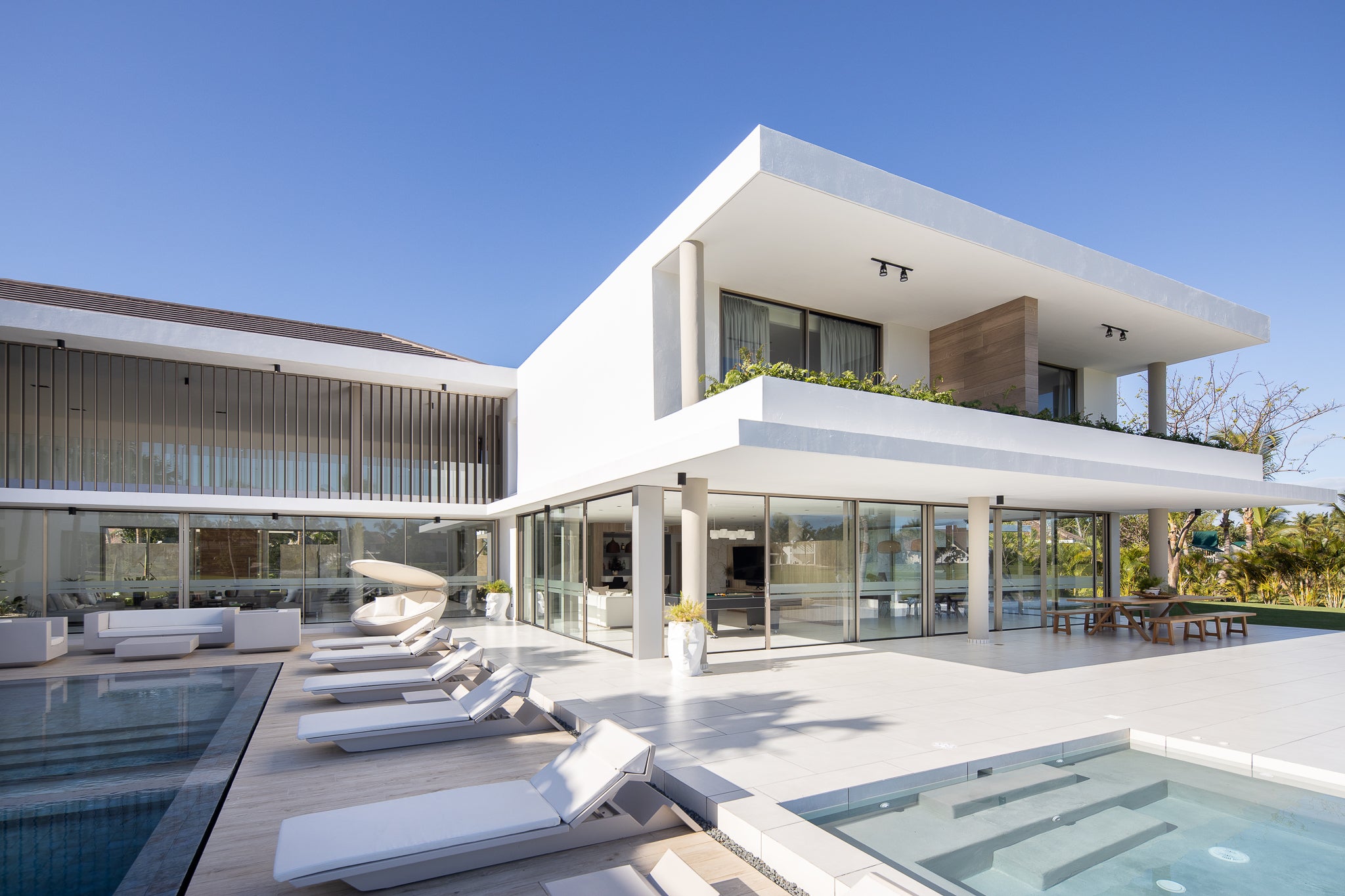Stunning luxury open plan villa with a two swimming pools. modern luxury Sunbeds, sofa and day beds surrounding them